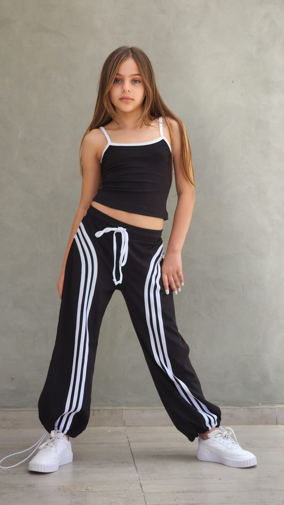 תקריב על מכנסי פסים שחורים לילדות עם גומי וסטופר בסוף הרגל מבית DUNE